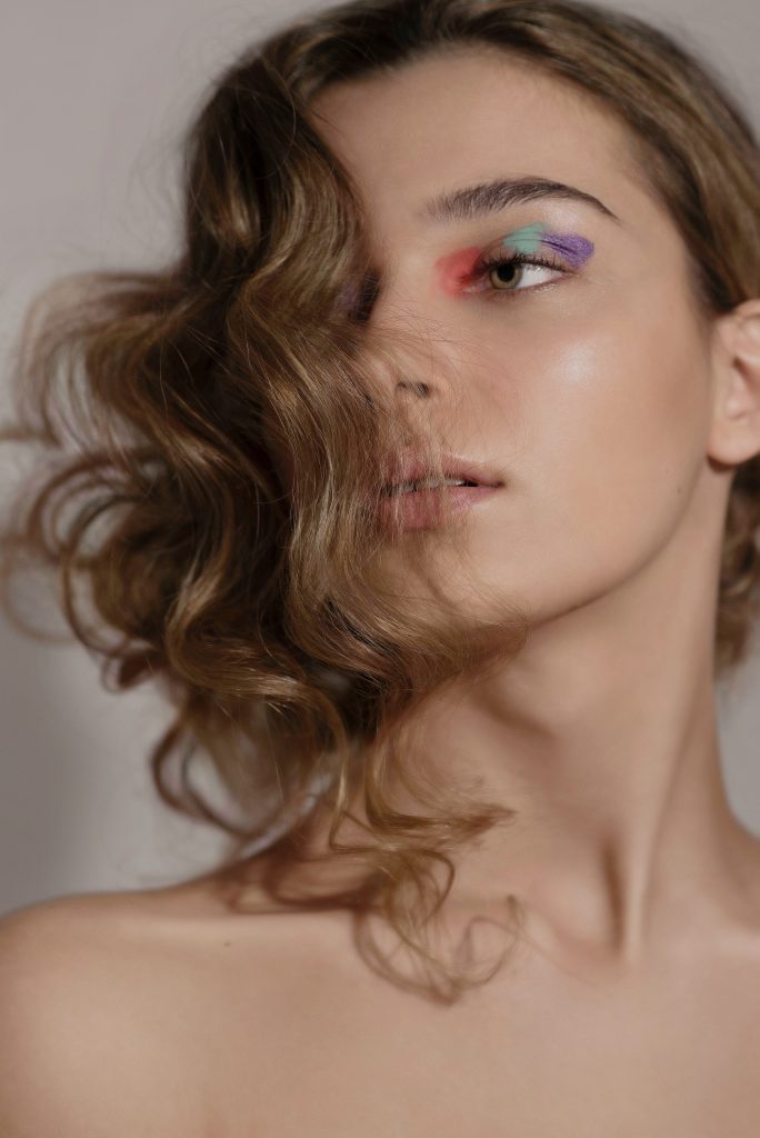 kreatives Beauty-Make-up mit orangenen, mintgrünen und lilafarbenen Details und welligem Hairstyle von Visagistin Eva Gerholdt