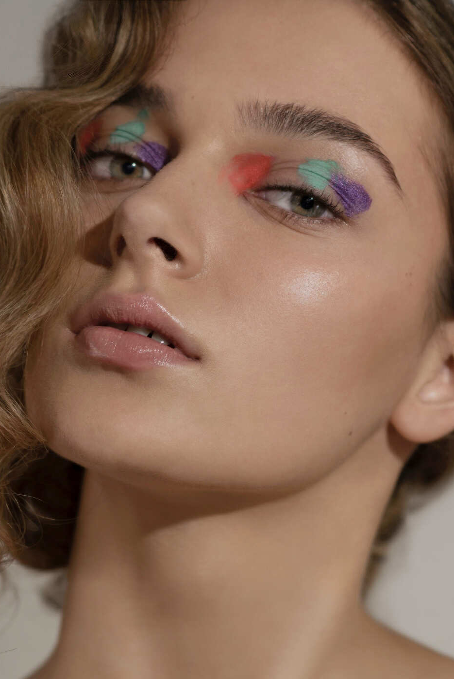 kreatives Beauty-Make-up mit orangenen, mintgrünen und lilafarbenen Details und welligem Hairstyle von Visagistin Eva Gerholdt