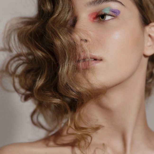 kreatives Beauty-Make-up mit orangenen, mintgrünen und lilafarbenen Details und welligem Hairstyle von Visagistin Eva Gerholdt